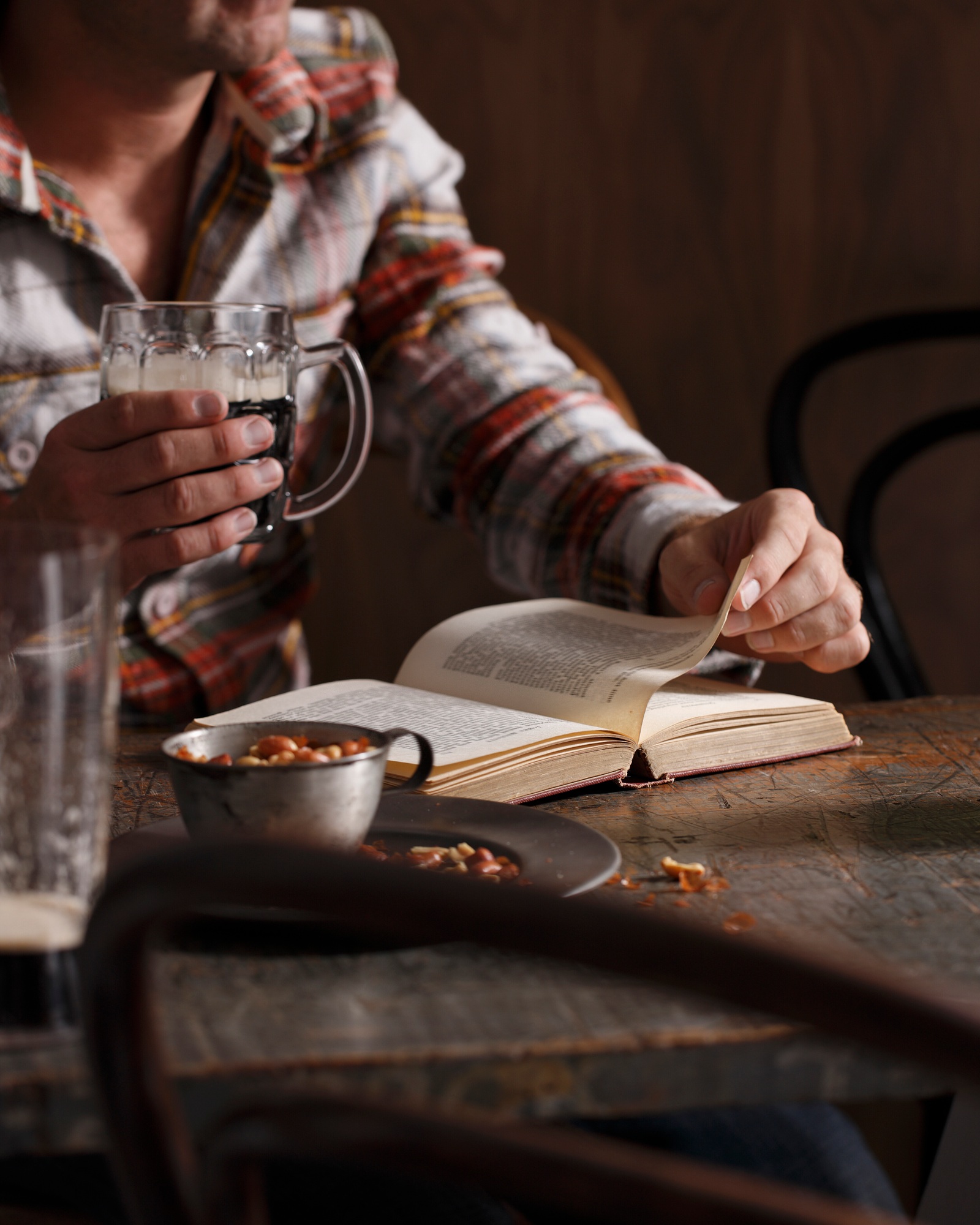 Person reading a book with a drink and snack on the table.